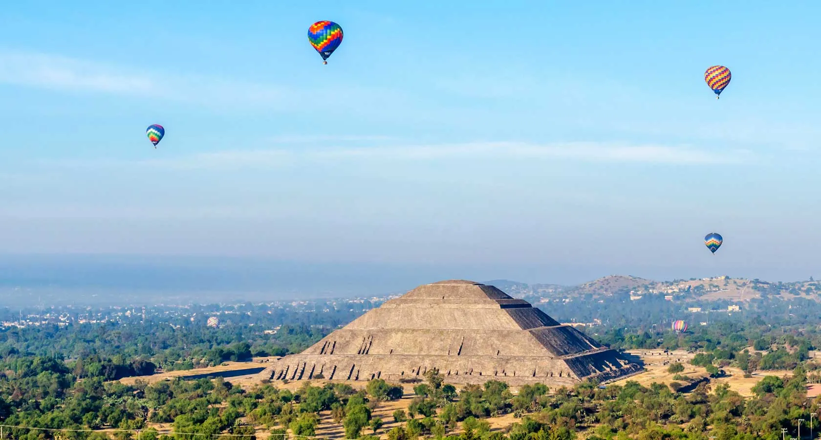 Hot air balloons over Teotihuacan in Mexico, pyramids and sunrise