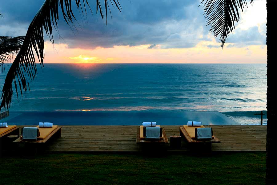 Golden sunset at Kenoa Exclusive Beach Spa & Resort, ocean and palms against the sky
