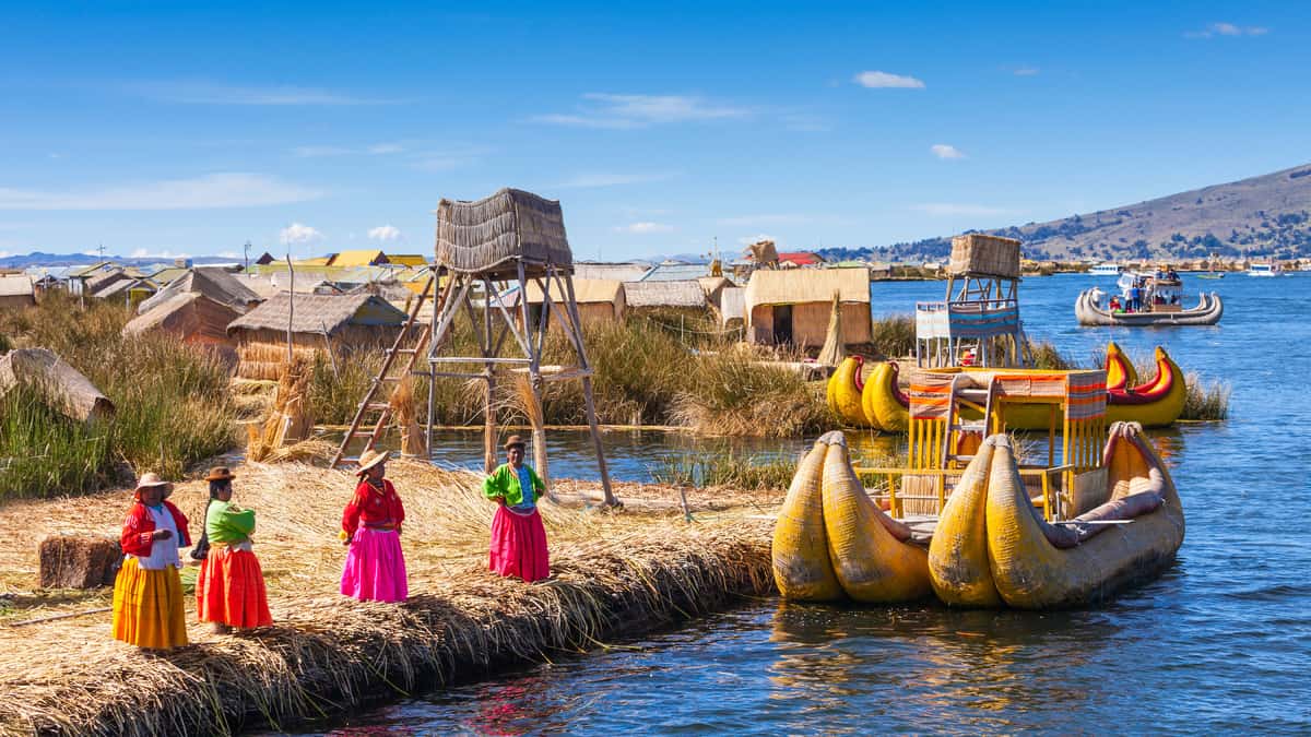 Reed buildings, local people and boats beside the water in the Puno area.