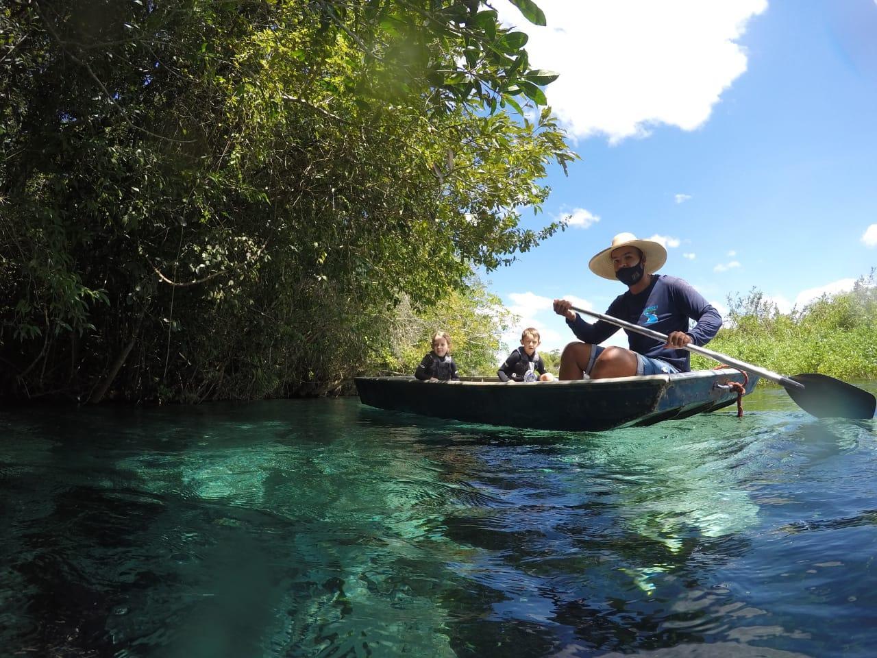 A family paddling a boat on a crystal-clear river near Bonito, Brazil.