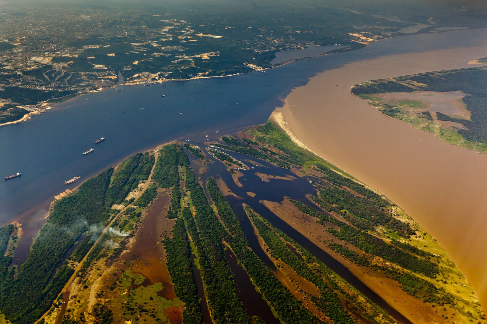 Aerial view of the meeting of the waters river confluence and port traffic near Manaus, Brazil.