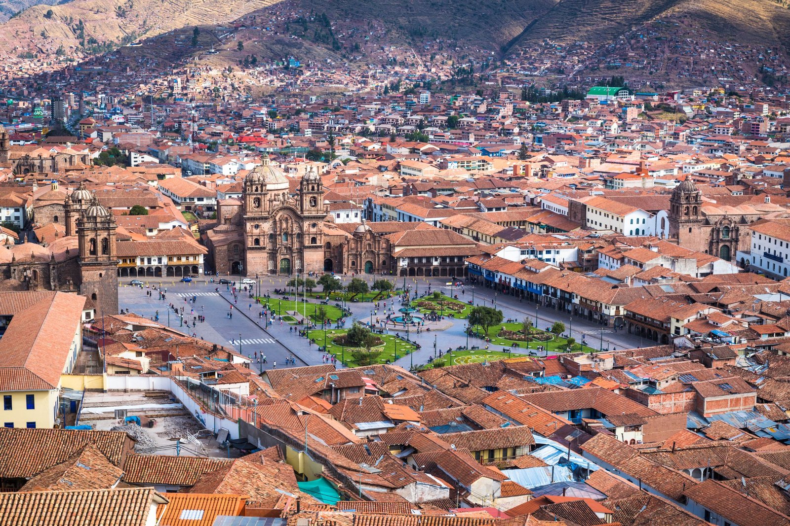 Aerial view of Cusco's historic center and the Plaza de Armas, with red tile roofs below the Andes.