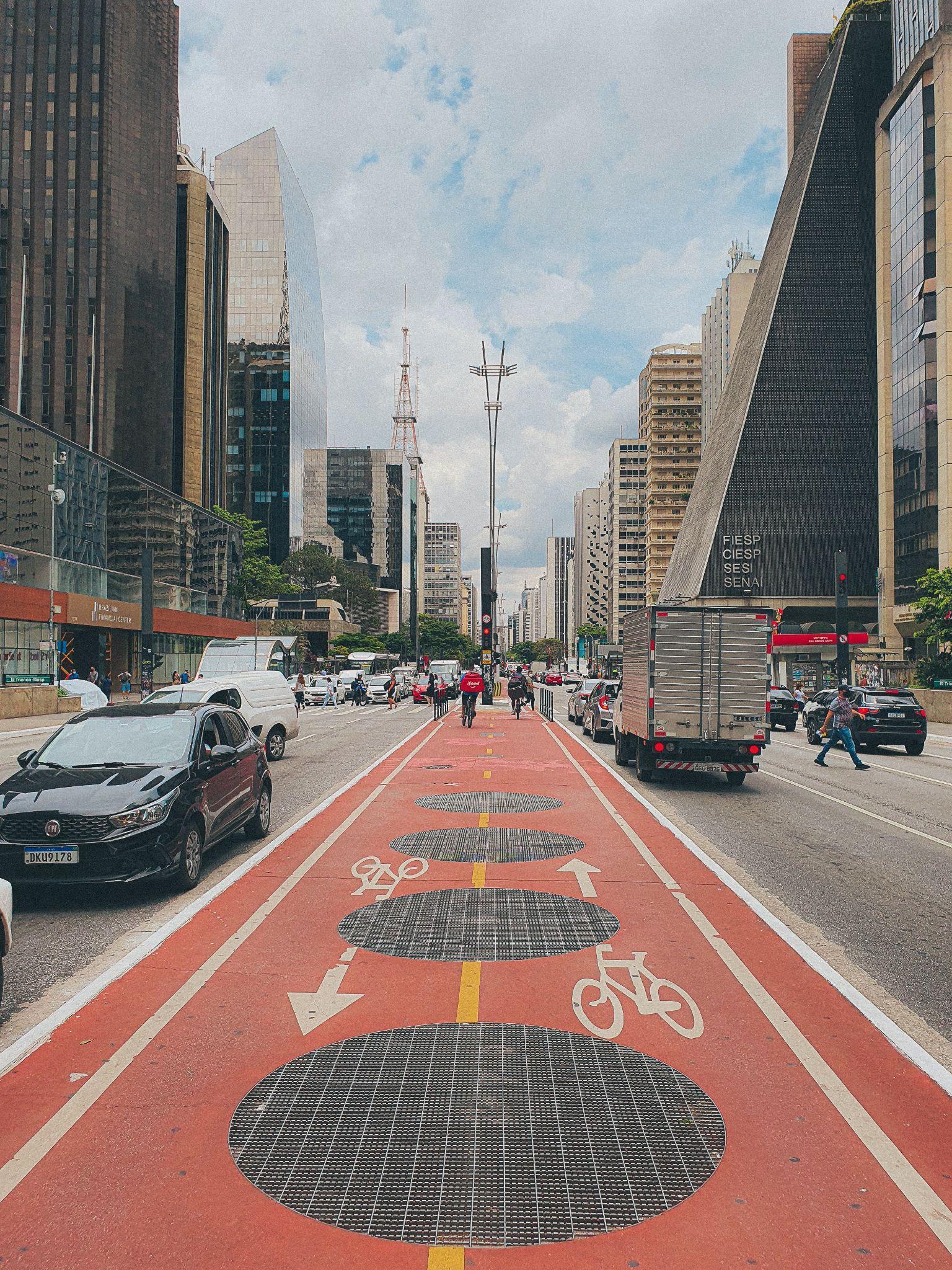 A protected bicycle lane on Avenida Paulista in São Paulo's business district, with office towers lining both sides of the avenue.