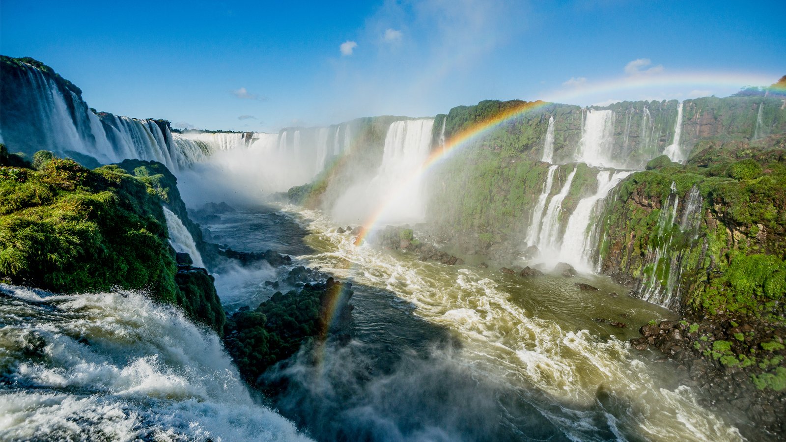 Iguaçu Falls in Brazil, with a wide rainbow arching over the cascades.