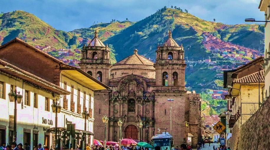 A street in Cusco leading towards a stone church, with densely built hills behind.
