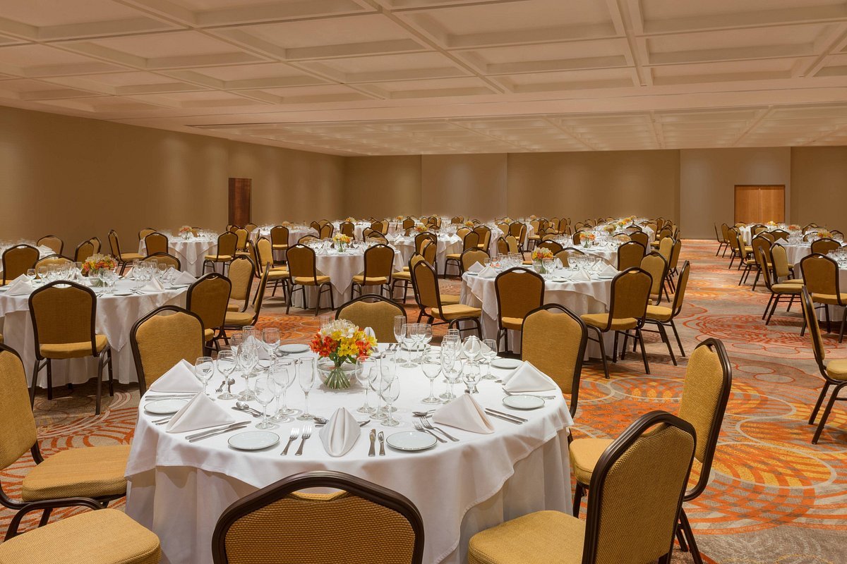 A hotel ballroom laid out with round, white-clothed tables for a group dinner.