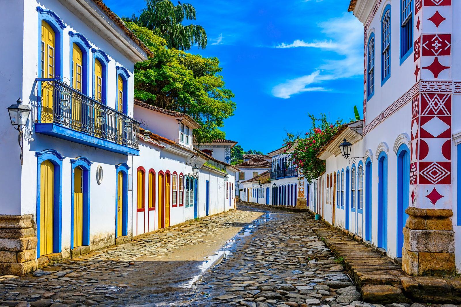 Colourful colonial street in Paraty with cobblestones and forested mountains