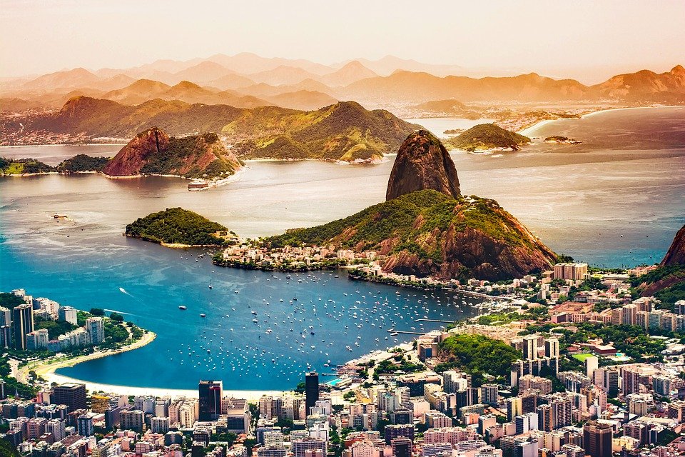 Aerial view of Rio de Janeiro, with Sugarloaf Mountain and Guanabara Bay in the foreground and the city spread along the coast.